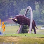 Large bull sculpture at Red Bull Ring circuit with lush green backdrop.